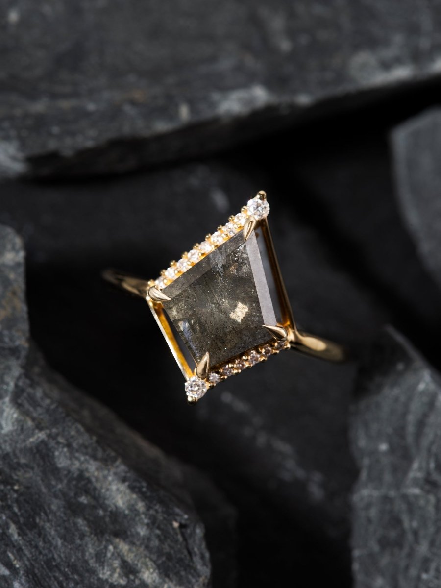 Gold ring with a large central stone and smaller stones on a dark background