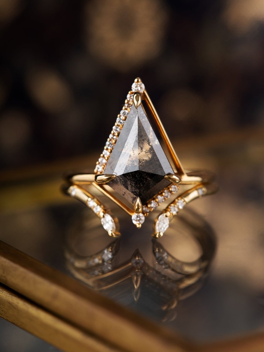 Gold ring with a large triangular gemstone on a reflective surface