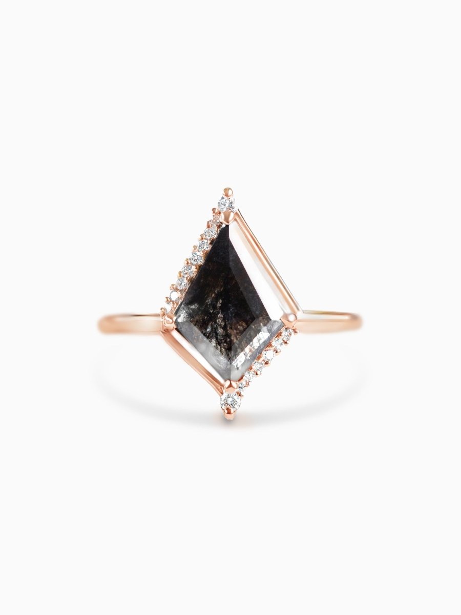 A geometric-inspired engagement ring with a polished kite-shaped salt and pepper diamond at the center, set in a rose gold band with smaller bright diamonds along the edges.