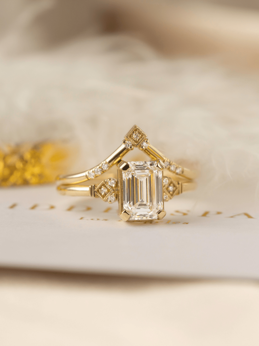gold emerald cut diamond ring on white envelope on white background