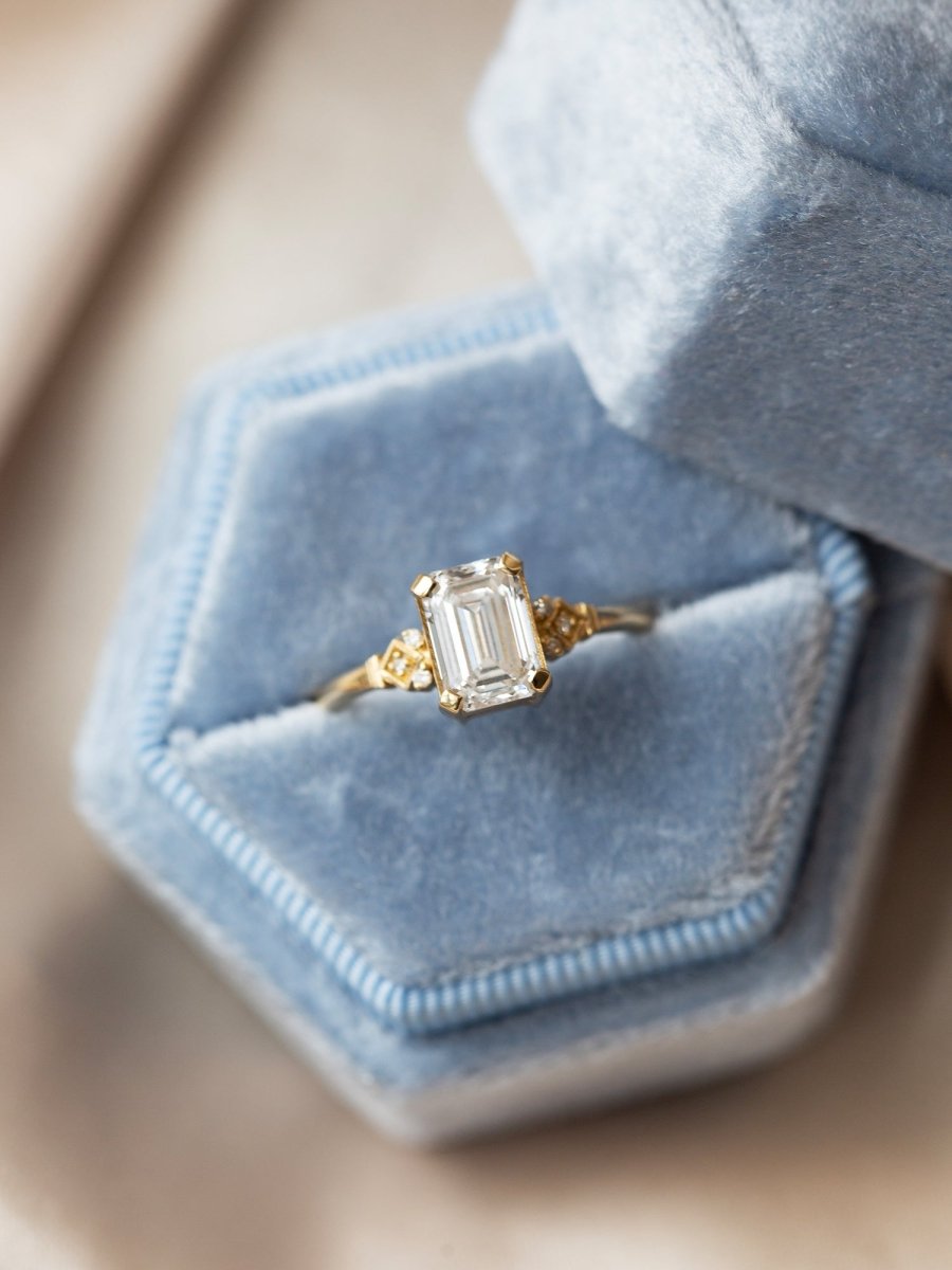 Gold ring with a large diamond in a hexagonal blue velvet box
