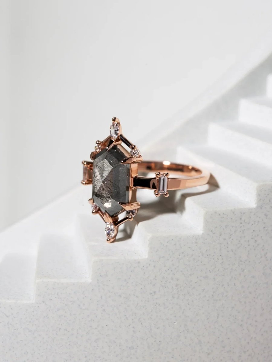 Rose gold ring with a large diamond and smaller diamonds on a light background