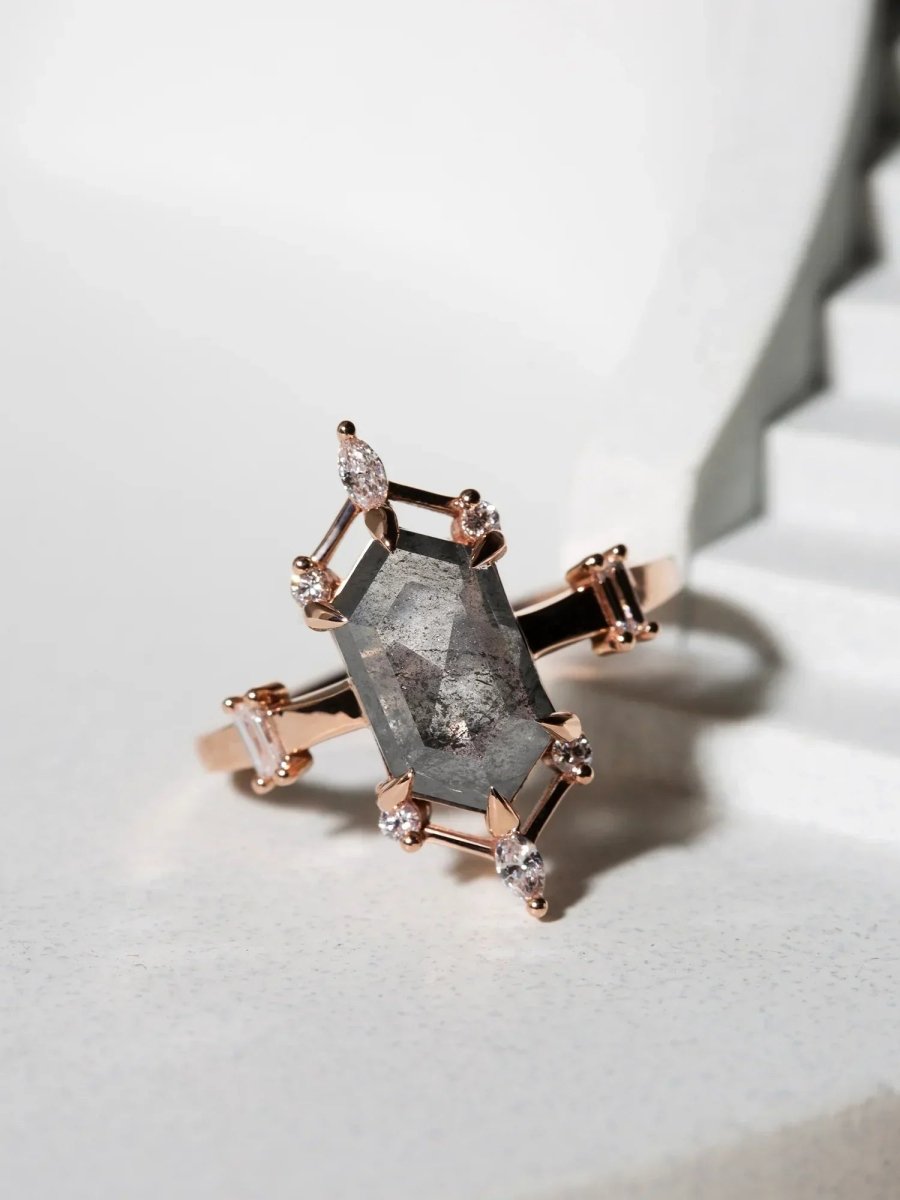 Rose gold ring with a large central gemstone and smaller diamonds on a light background