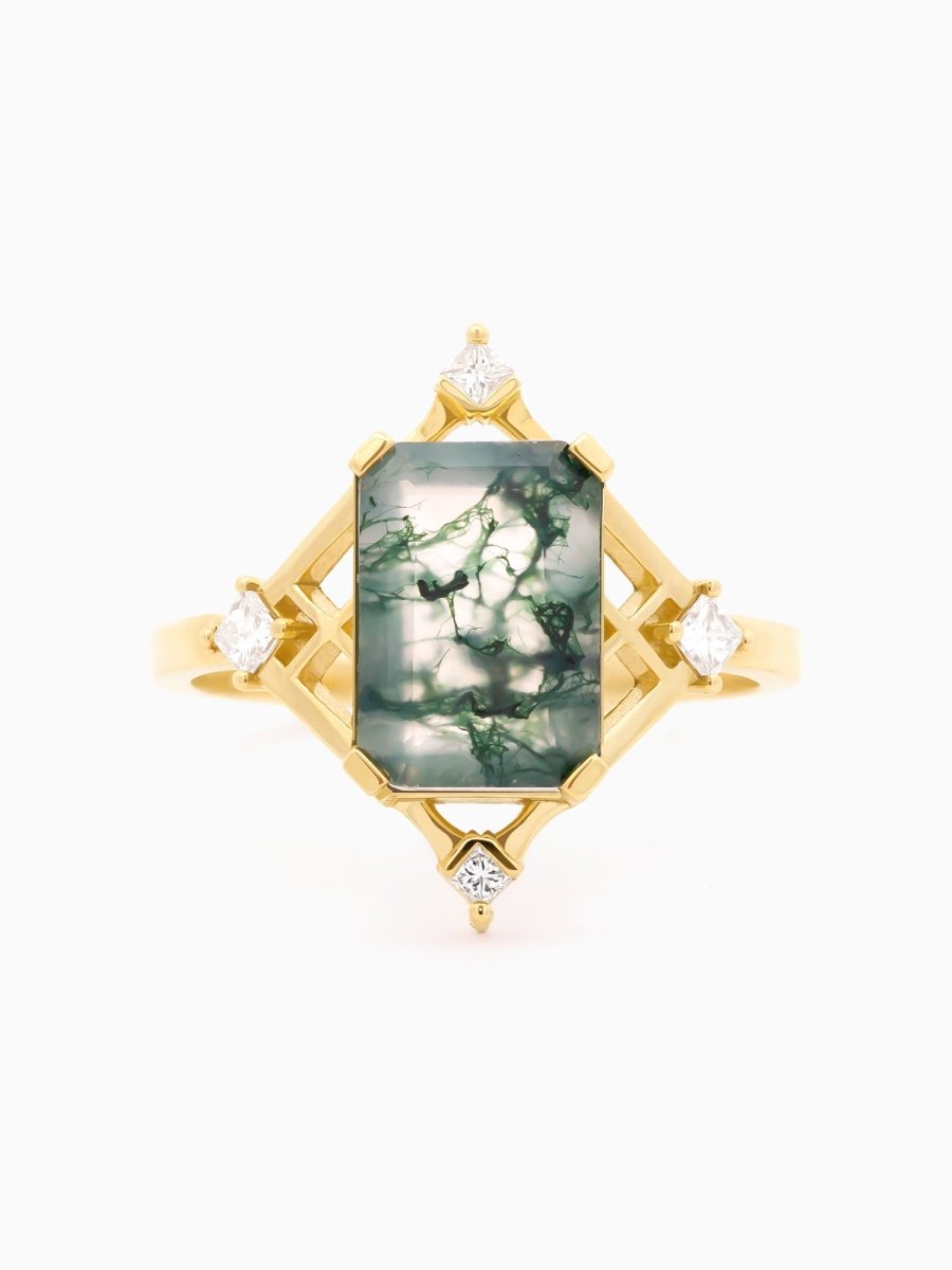 Face view of gold ring with emerald-cut moss agate centered above gold compass-shaped lattice
