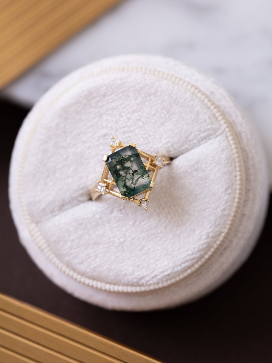 Gold ring with a green gemstone on a white cushion