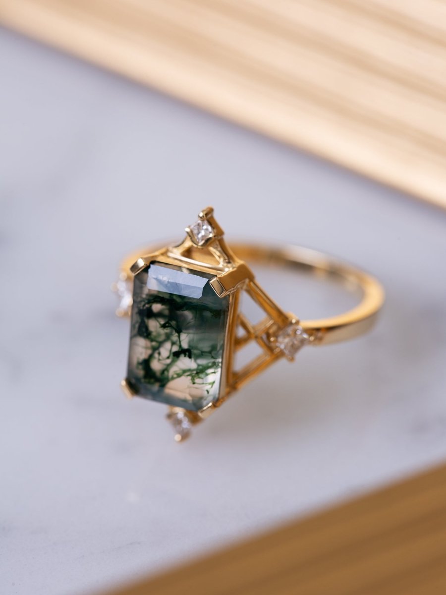 Gold ring with a green gemstone on a light gray background