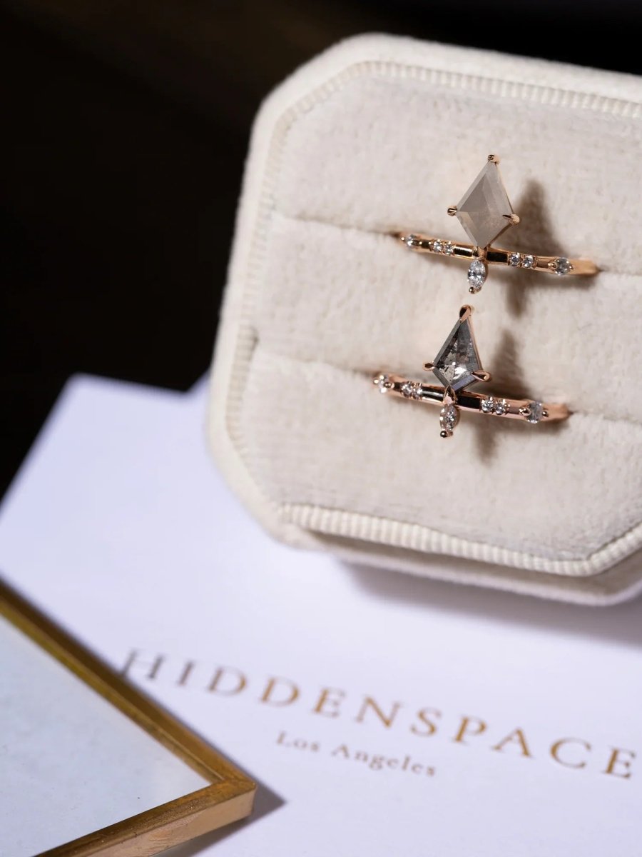 Pair of star-shaped earrings on a white jewelry case with 'Hiddenspace Los Angeles' book in the background.