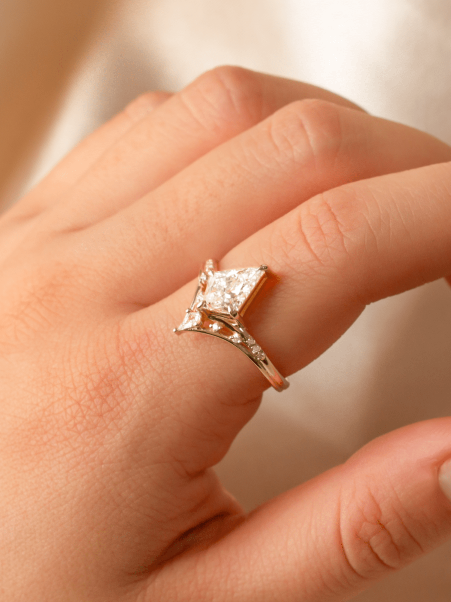 Rose gold ring with a diamond on a hand against a neutral background
