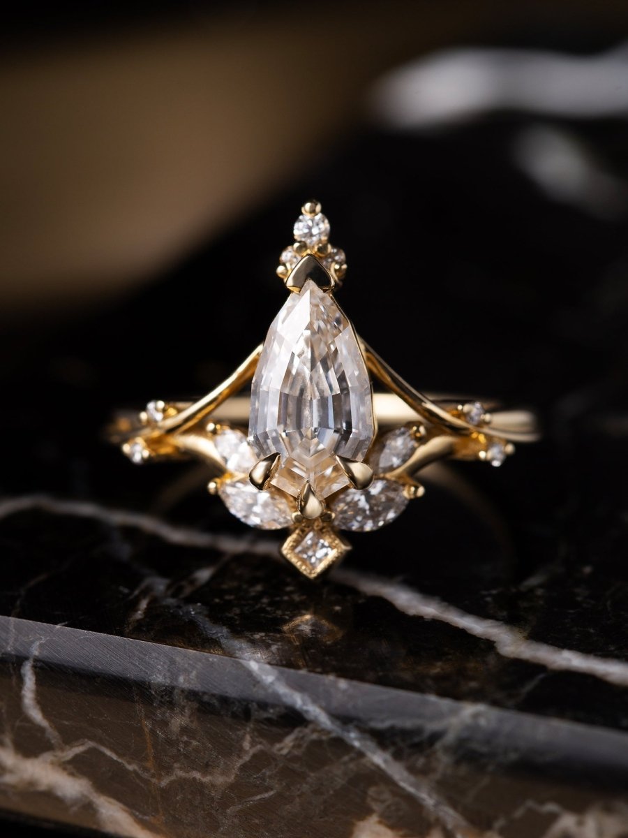 Gold ring with a large pear-shaped diamond on a dark marble surface