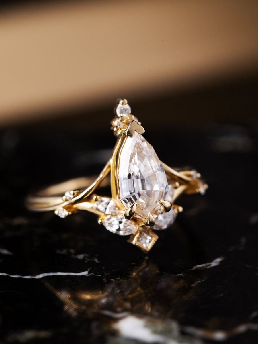 Gold ring with a large pear-shaped diamond on a dark background