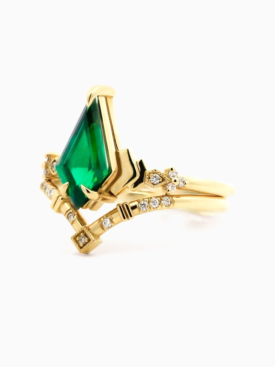 side of Art Deco engagement ring with kite emerald, stepped chevron shoulders, milgrain accents, and chevron band