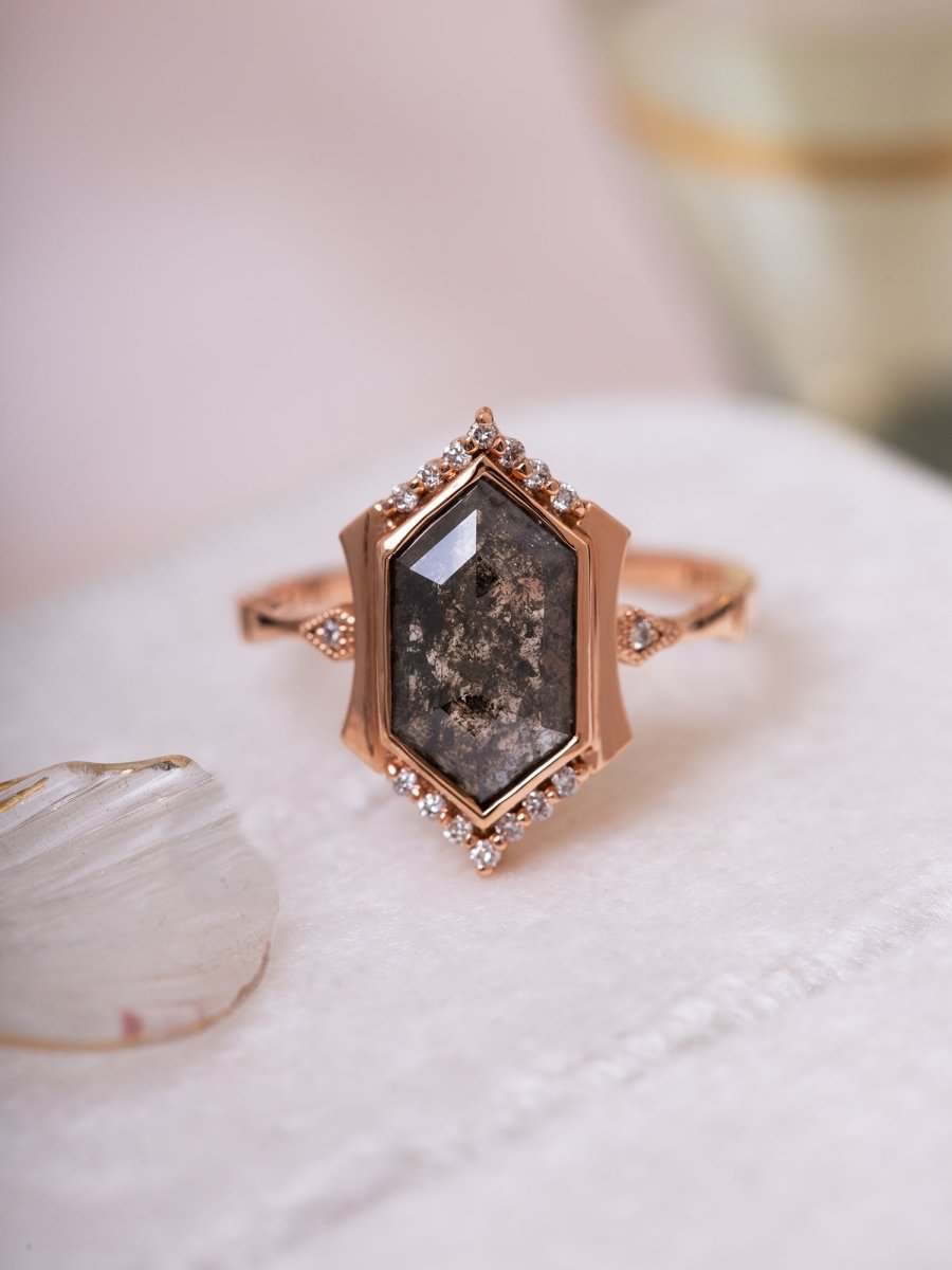 Rose gold ring with a large central stone and smaller stones on a white surface