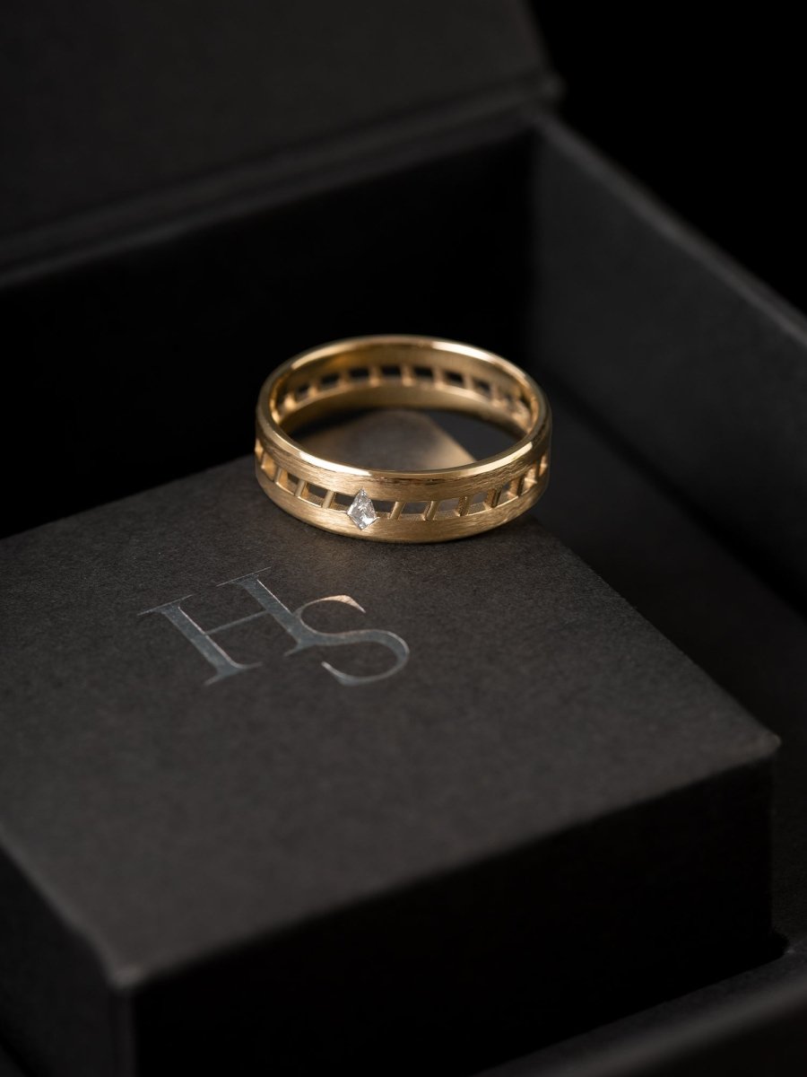 Gold ring on a black box with 'HS' initials