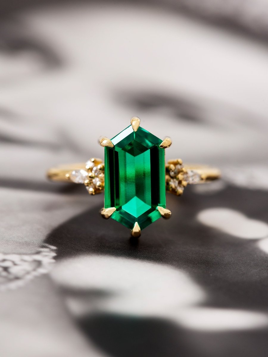 Gold ring with a green emerald stone on a textured surface