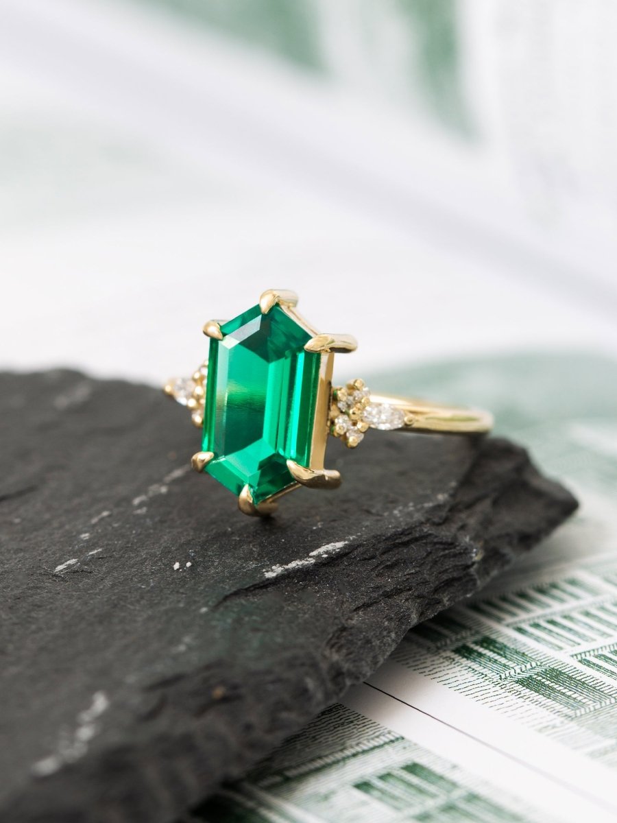 Gold ring with a green emerald stone on a dark surface