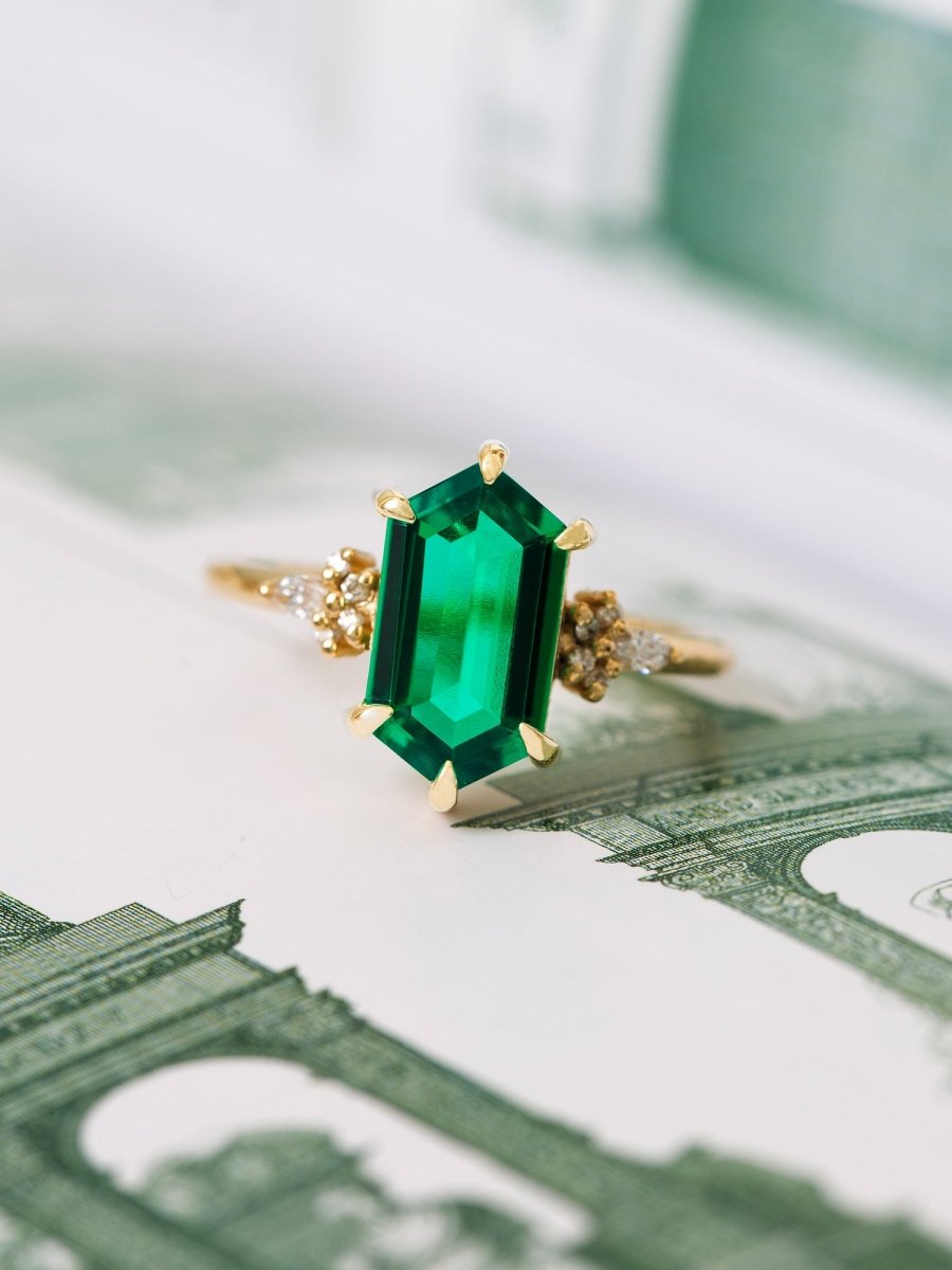 Gold ring with a green gemstone on top of U.S. dollar bills