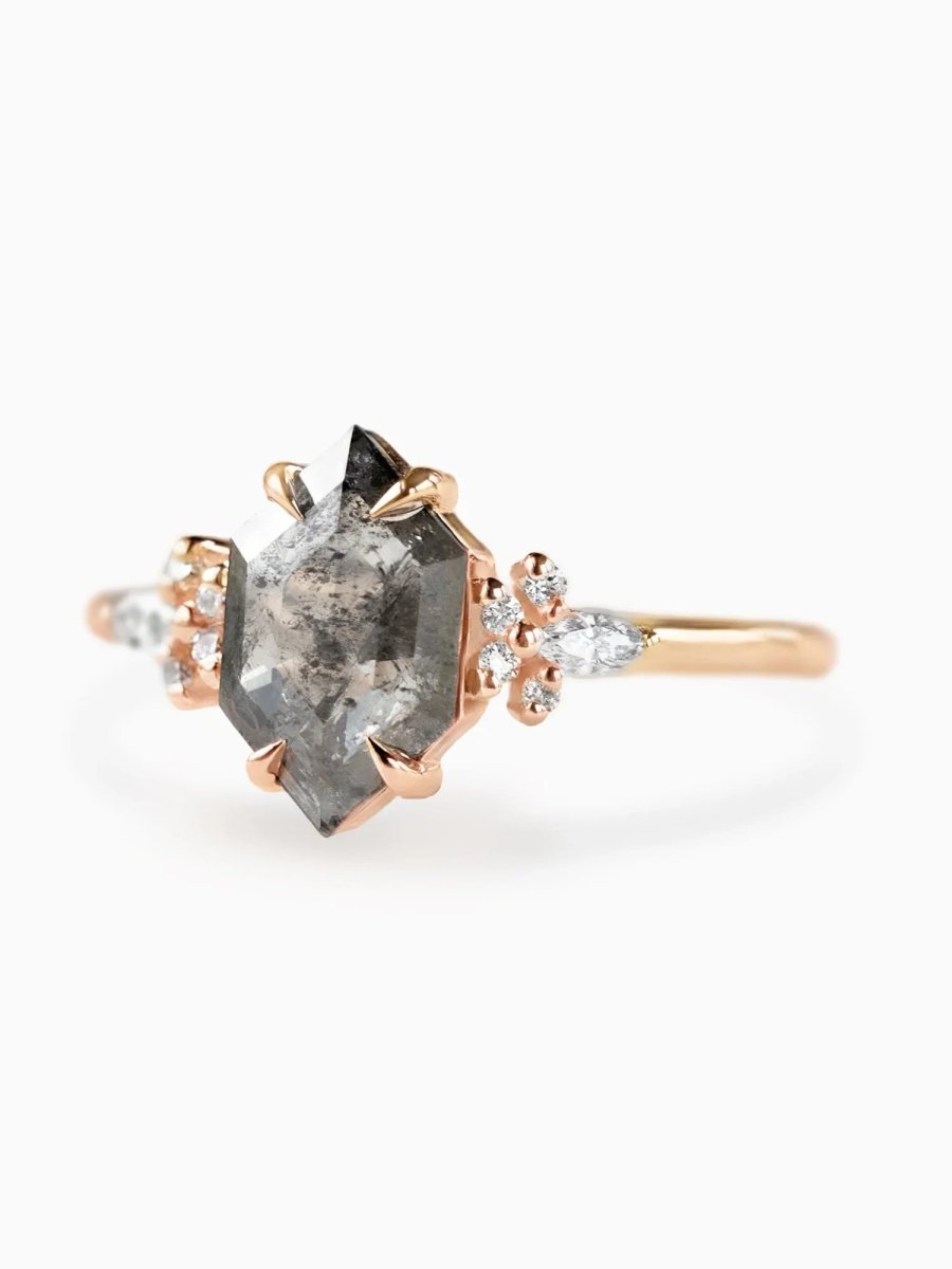 Rose gold ring with a large grayish diamond and smaller diamonds on a white background