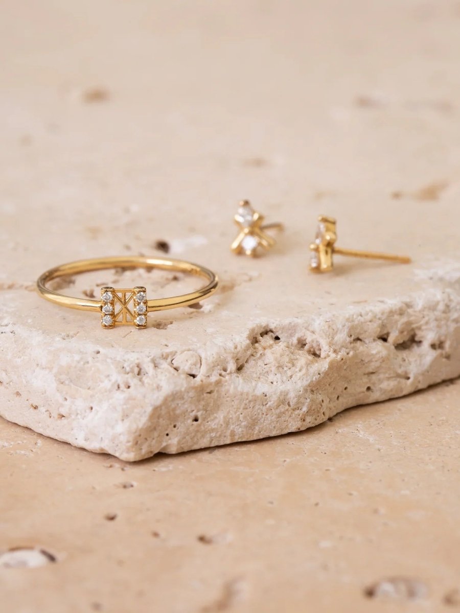 Gold bracelet and earrings on a textured stone surface