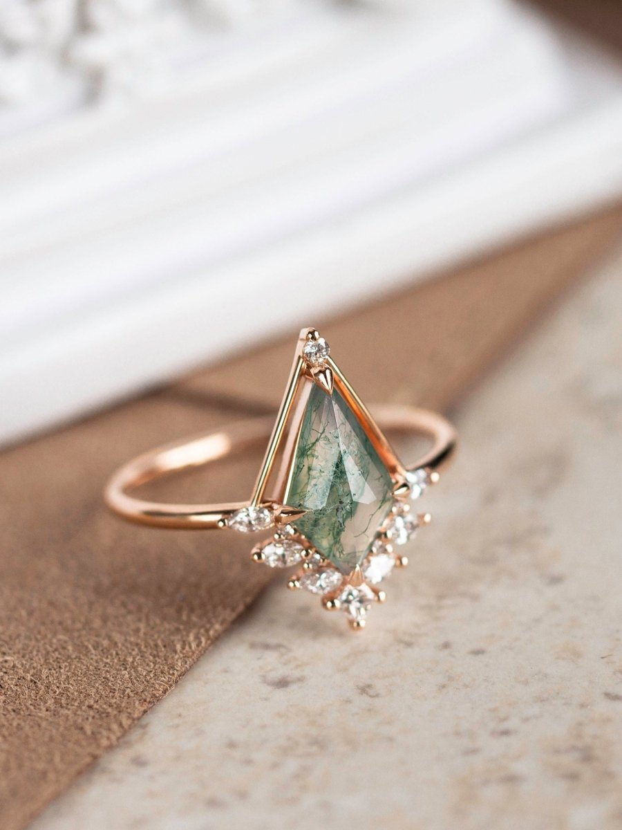 Rose gold ring with a green gemstone on a neutral background