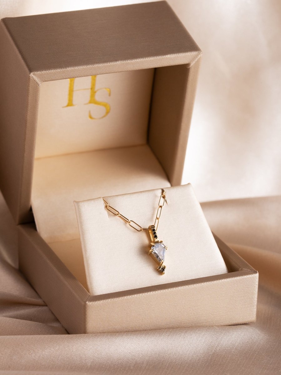 Gold bracelet with a heart charm in an open beige jewelry box with 'IFS' branding.