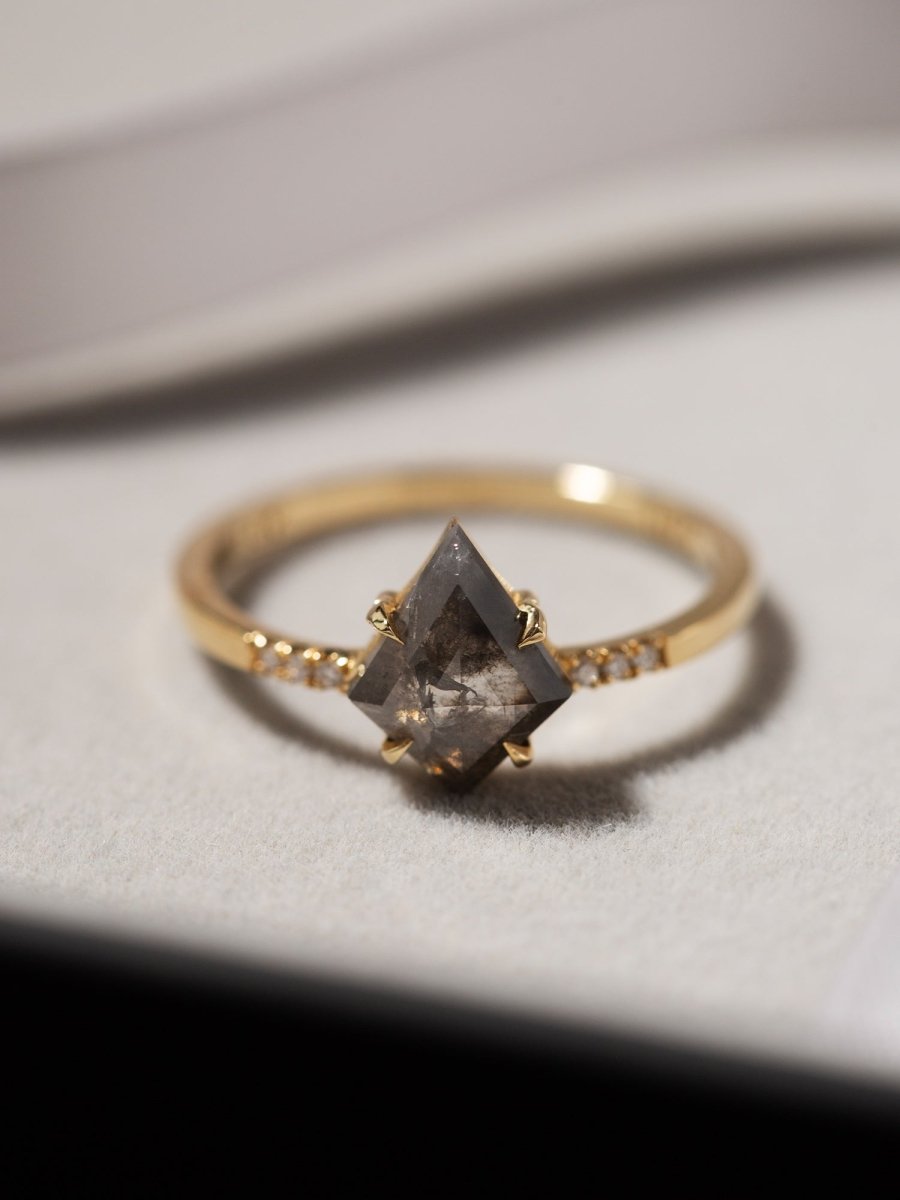 Gold ring with a dark gemstone on a light gray surface