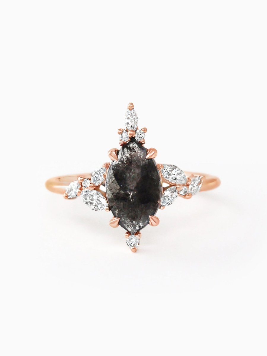 A marquise-cut salt and pepper diamond ring with a central diamond surrounded by smaller ones, set in a rose gold band