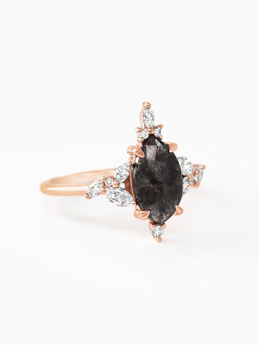 Rose gold ring with a black gemstone and diamonds on a white background
