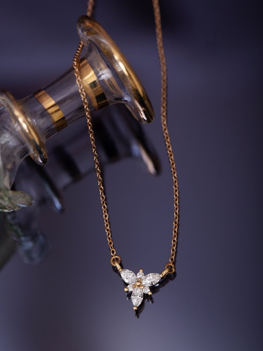 Gold necklace with a floral pendant on a dark background