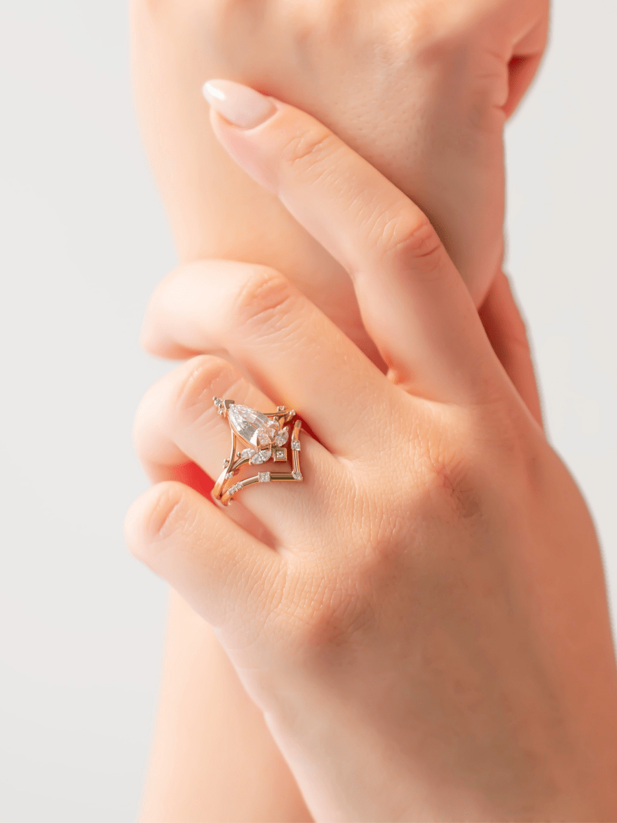 two hands wearing Art Nouveau engagement ring with marquise diamond, split shank, and chevron contour band