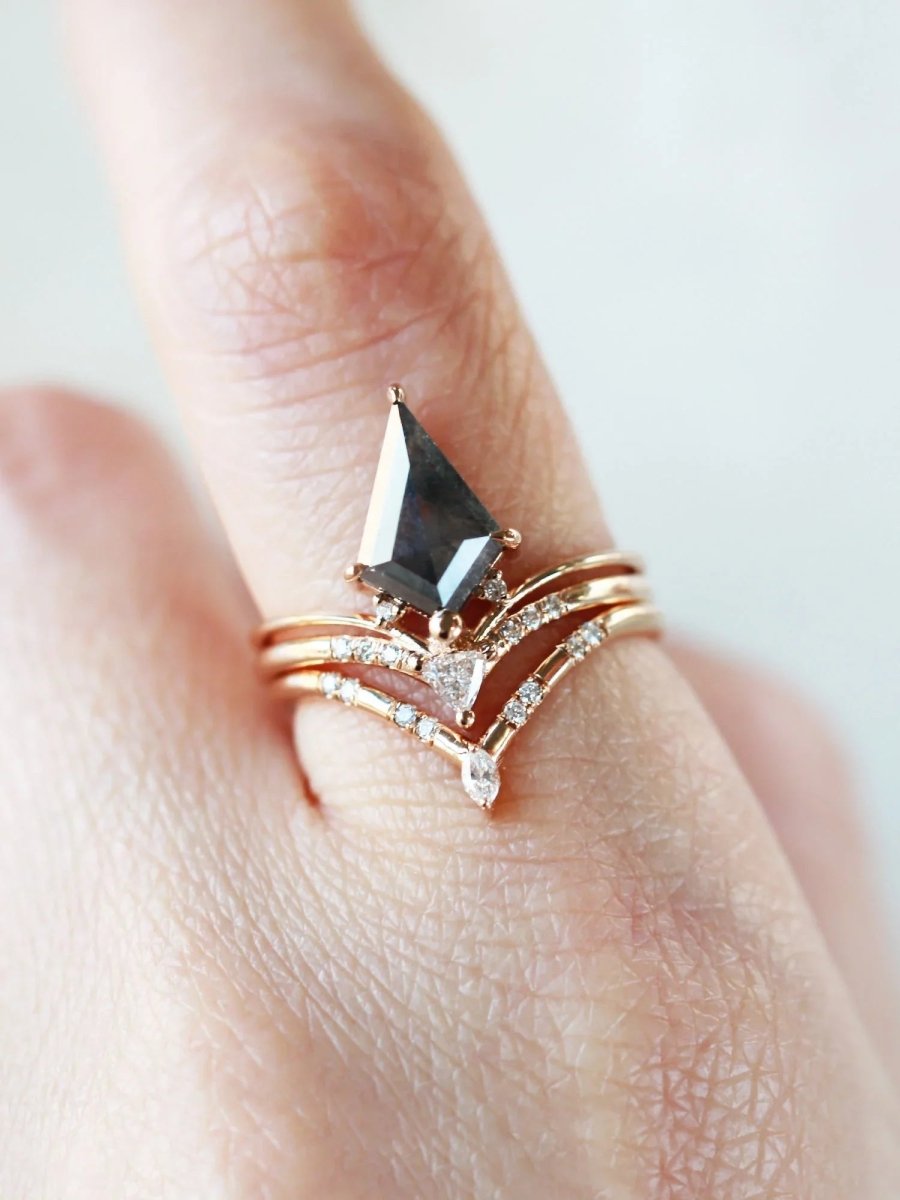 Minimalistic and art deco styled kite salt and pepper diamond engagement ring in 14k rose gold with a trilliant and round diamonds on model's hand.