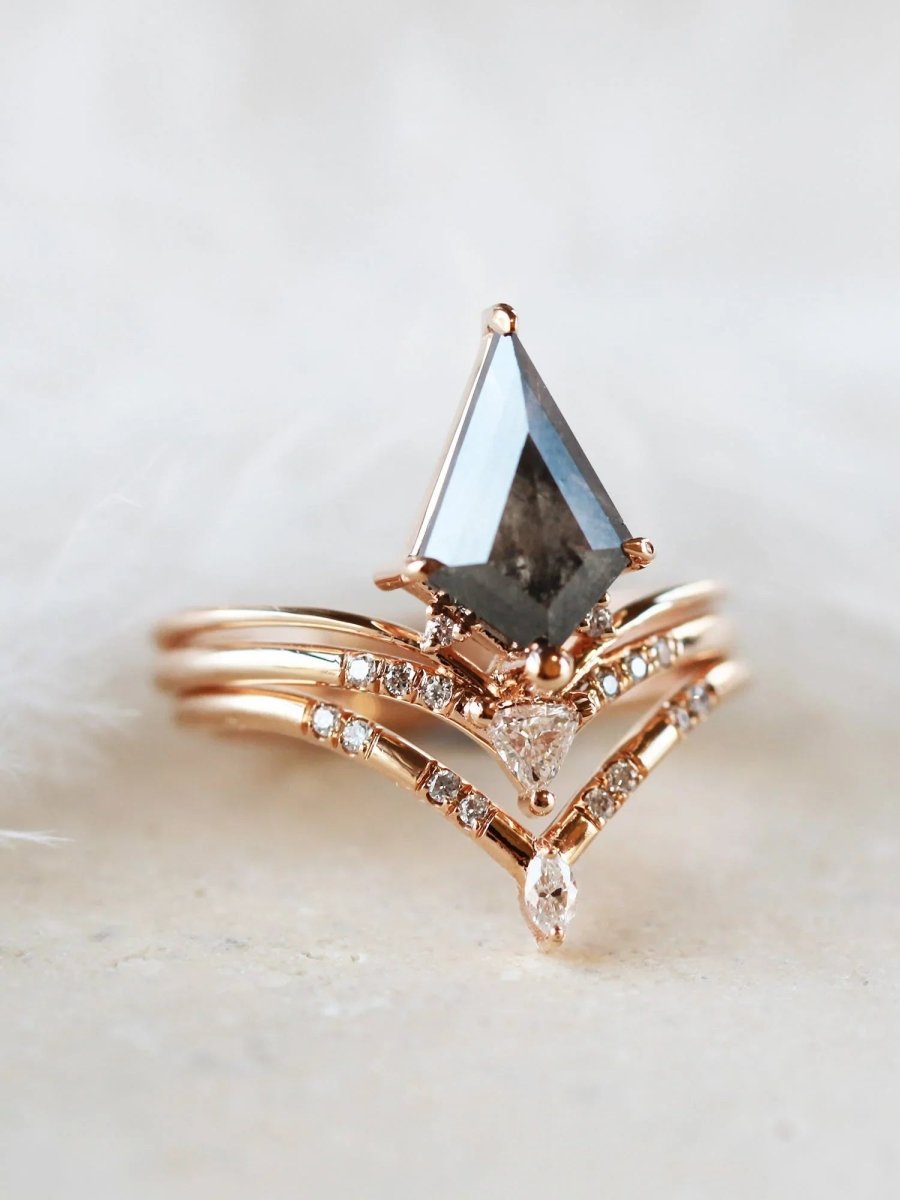 Minimalistic and art deco styled kite salt and pepper diamond engagement ring in 14k rose gold with a trilliant and round diamonds with matching band.