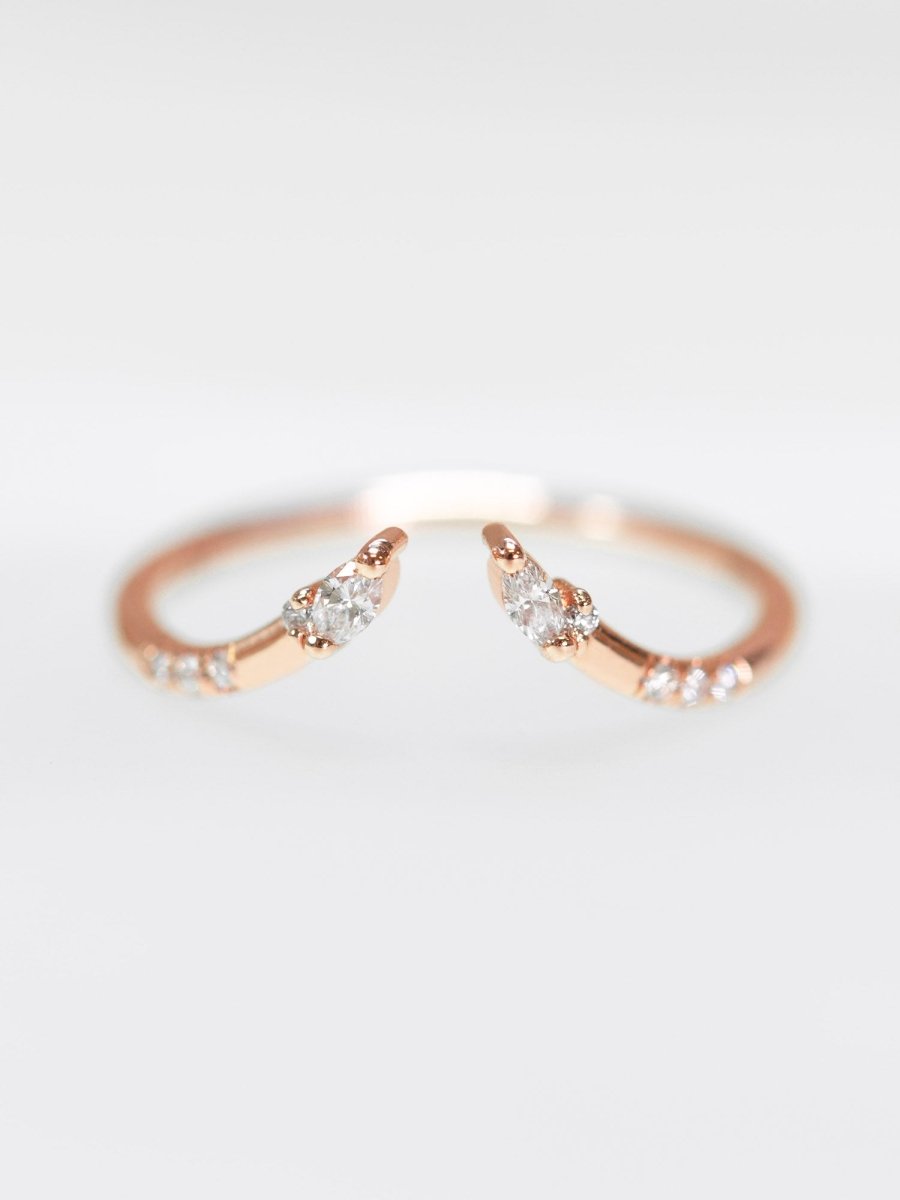 A rose gold-colored ring with small, possibly diamond-like stones set in a curved design.