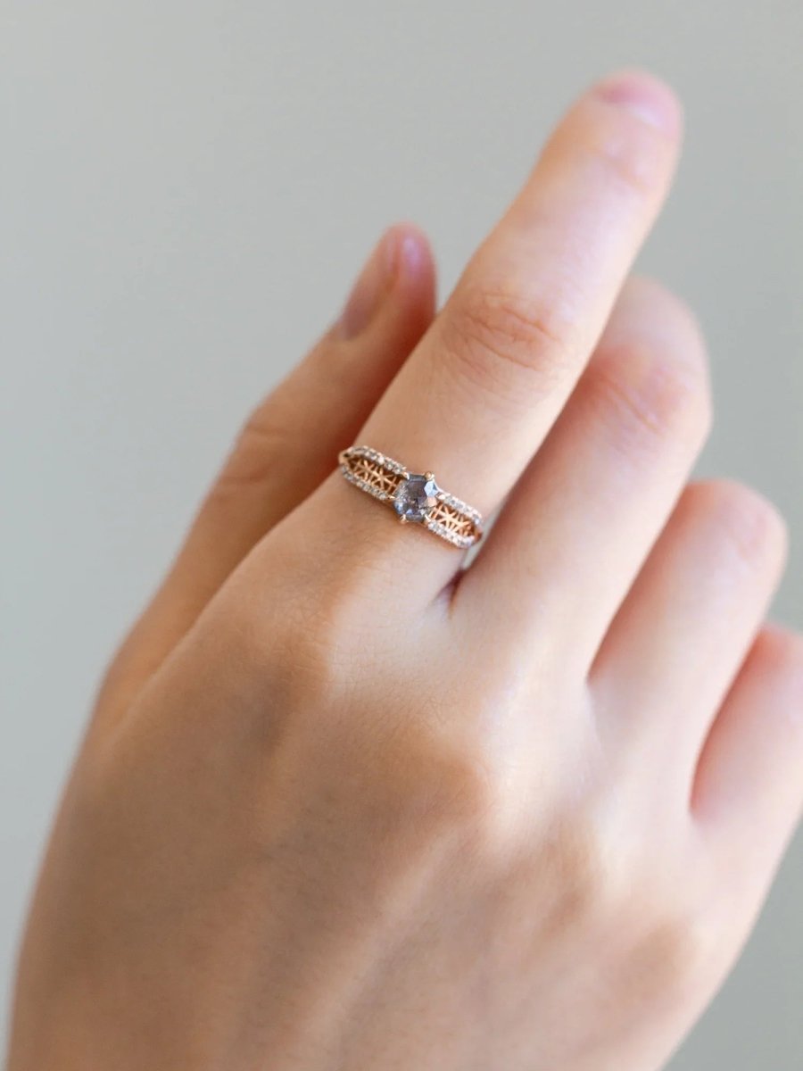 Relaxed hand wearing contemporary engagement ring on index finger, captured in soft natural lighting to highlight the salt pepper diamond and pave sparkle