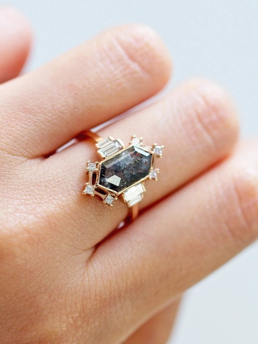 Ring with a large central gemstone and smaller diamonds on a finger against a light background