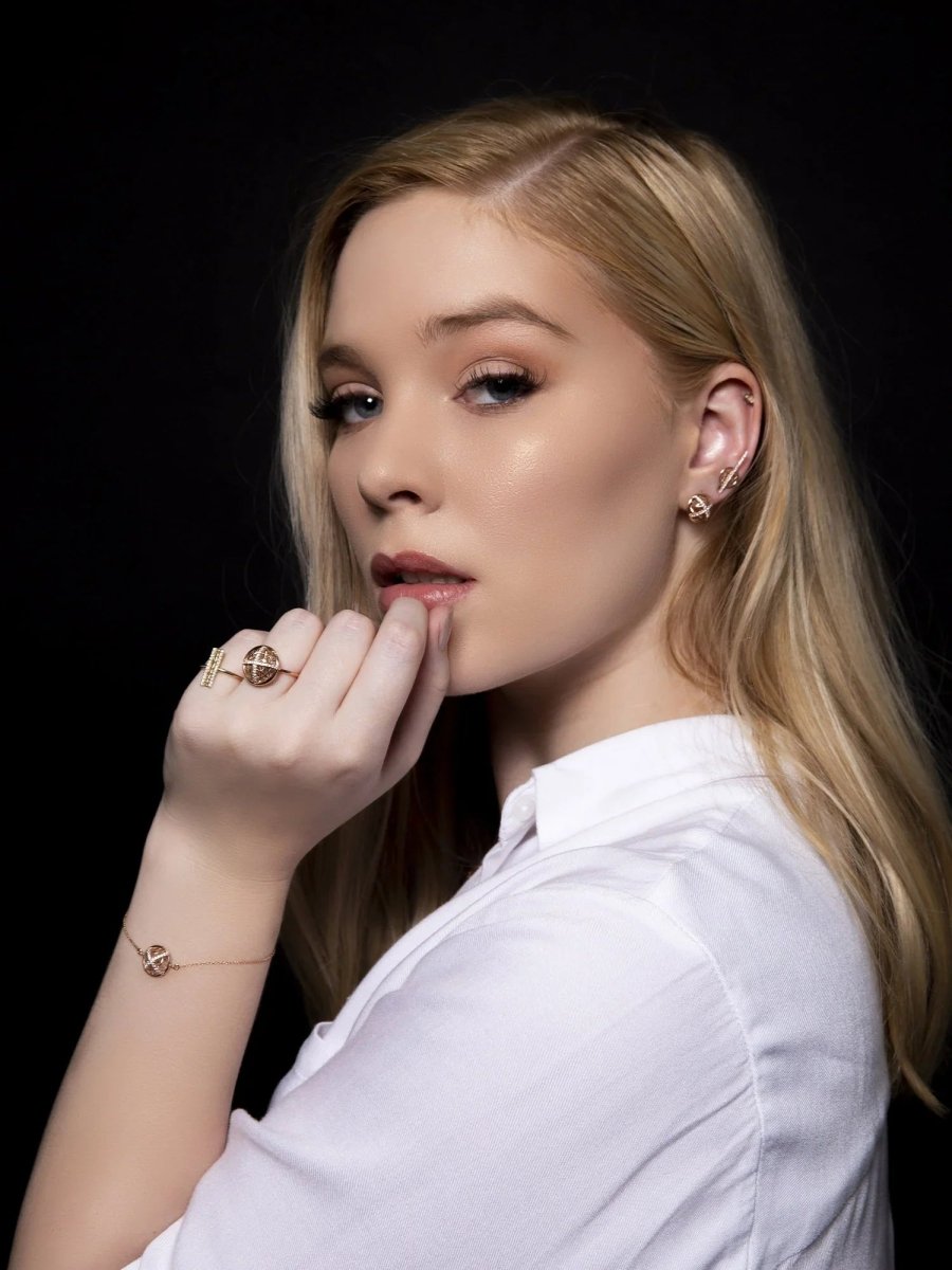 Woman wearing jewelry including a ring, bracelet, and earrings against a black background