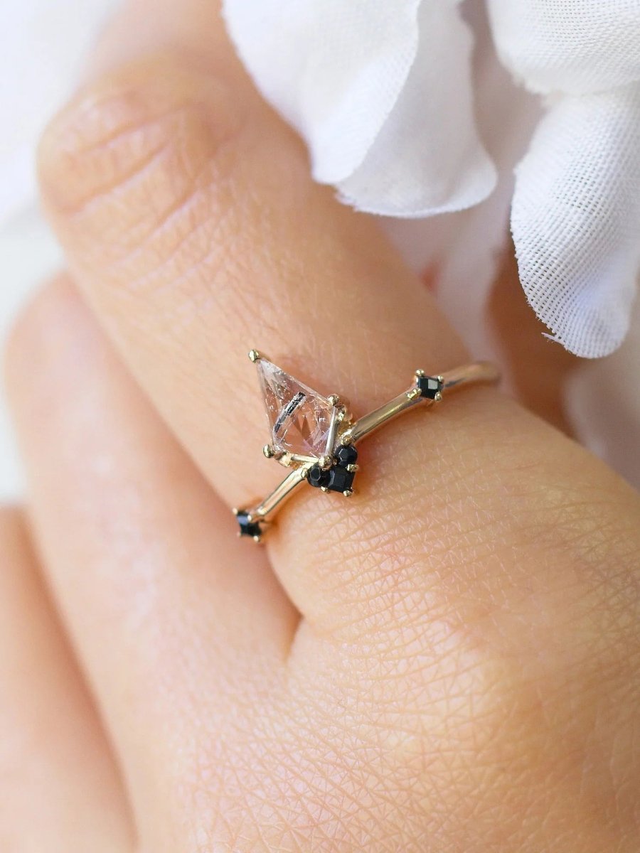 Close-up of index finger wearing minimalist Art Deco ring, gently caressing soft white fabric flower petals, showcasing fine details