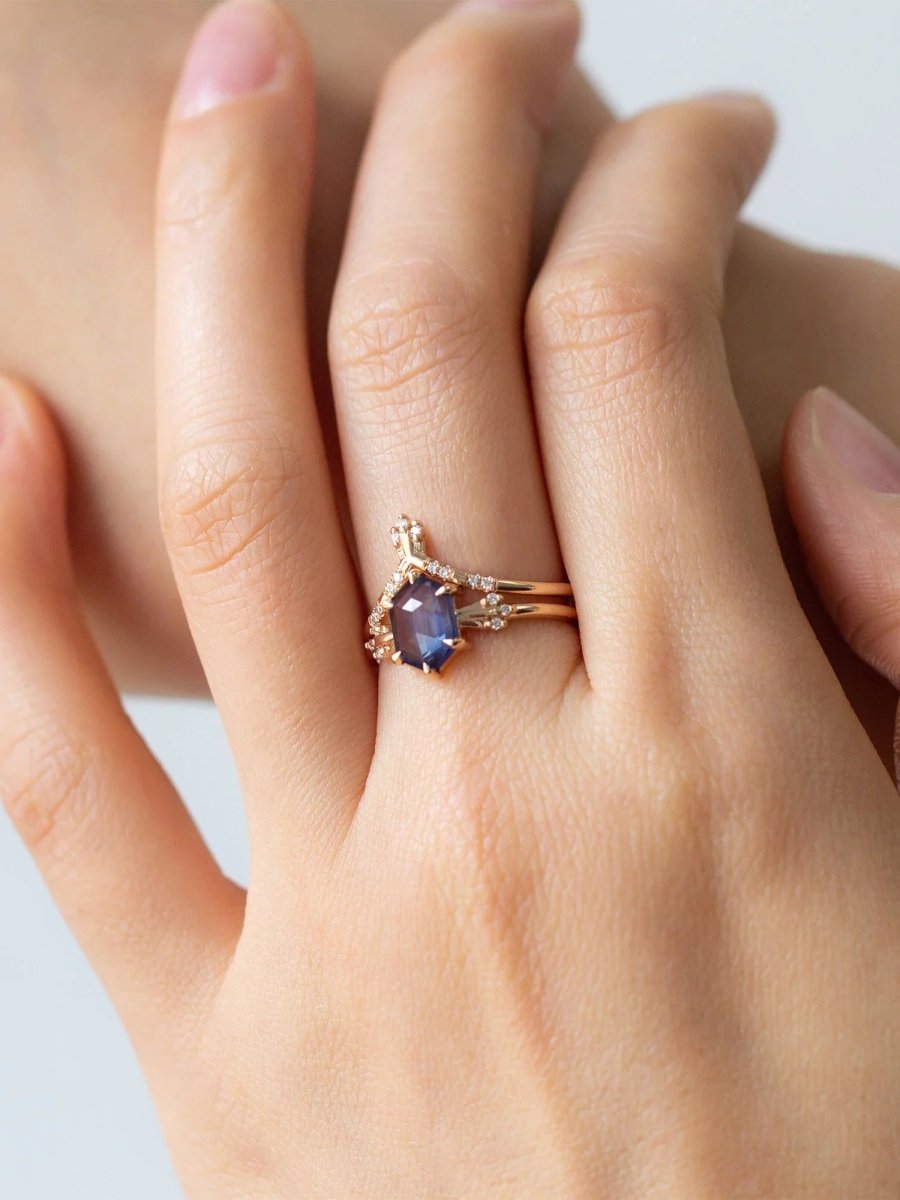 Rose gold ring with a gemstone on a hand against a neutral background
