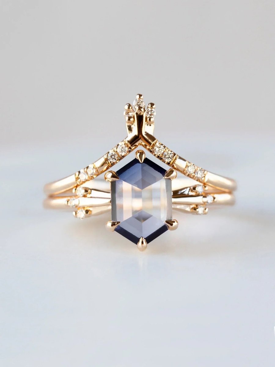 Gold ring with a central blue gemstone on a light gray background