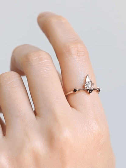 GIF of hand wearing minimalist Art Deco ring on index finger, turning to showcase sparkling facets and onyx accents in motion