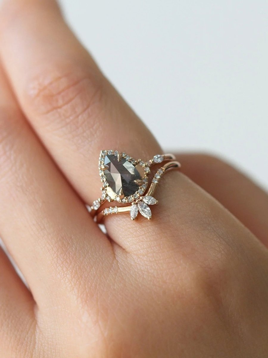 Pear-shaped salt and pepper diamond engagement ring in 14k rose gold inspired by the art deco style and minimalism on model's hand.