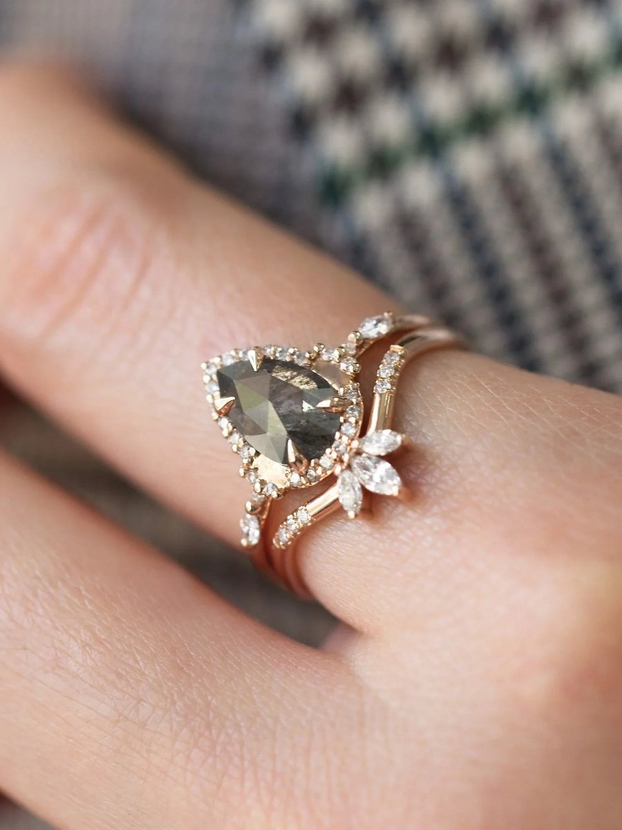 Pear-shaped salt and pepper diamond engagement ring in 14k rose gold inspired by the art deco style and minimalism on model's hand.