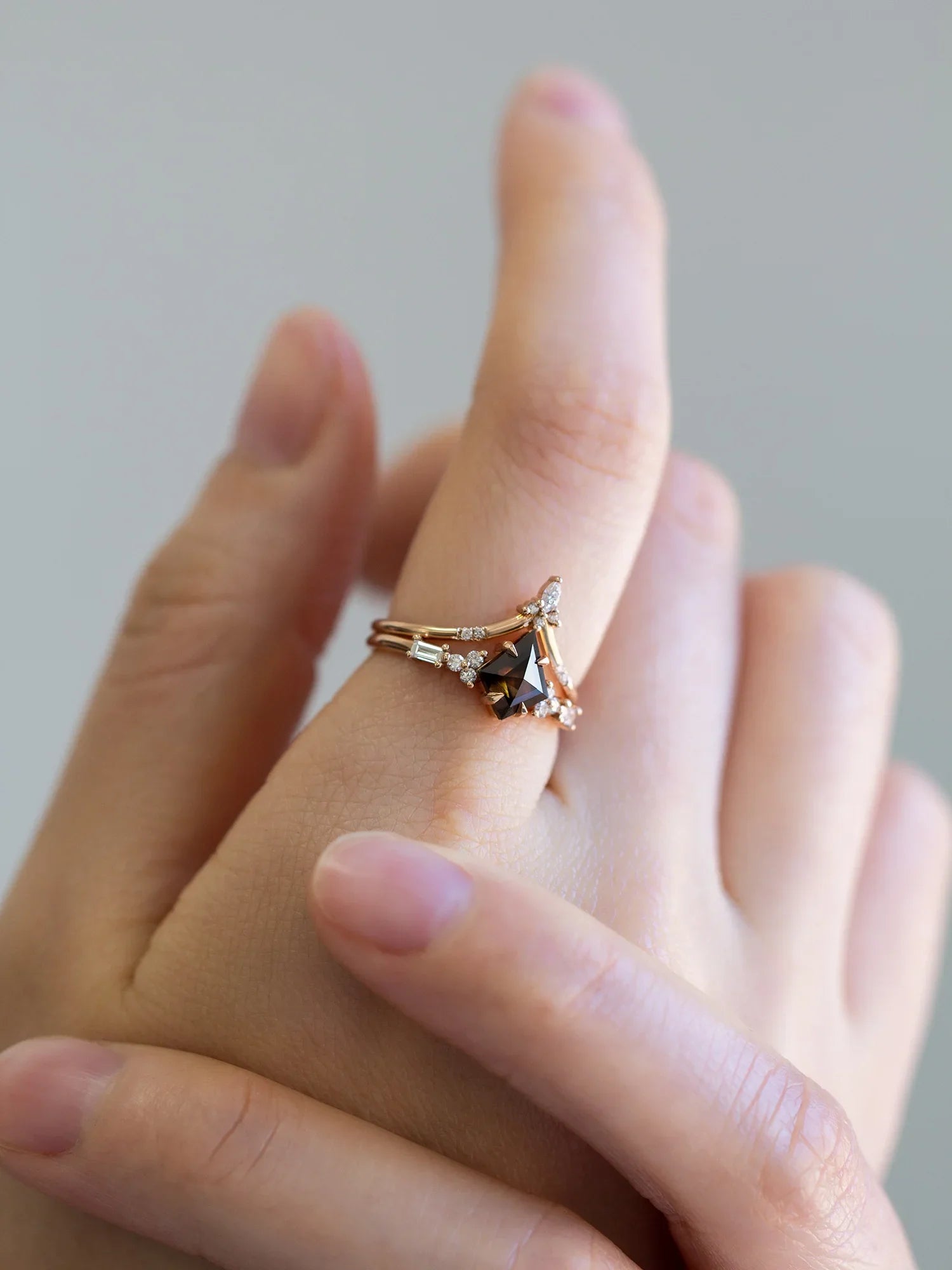 hand wearing petite ring with kite salt and pepper diamond, trefoil melee accents on shoulders, and baguette stones on band.