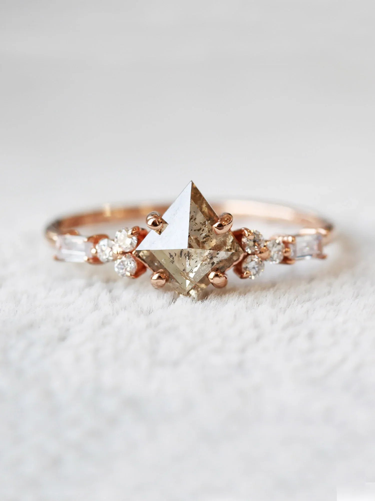 Face view of petite ring with white kite salt and pepper diamond, trefoil melee accents on shoulders, displayed on white rug.