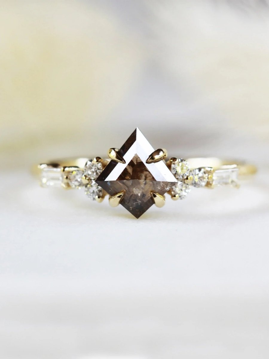 Face view of petite ring with brown kite salt and pepper diamond, trefoil melee accents on shoulders with yellow background