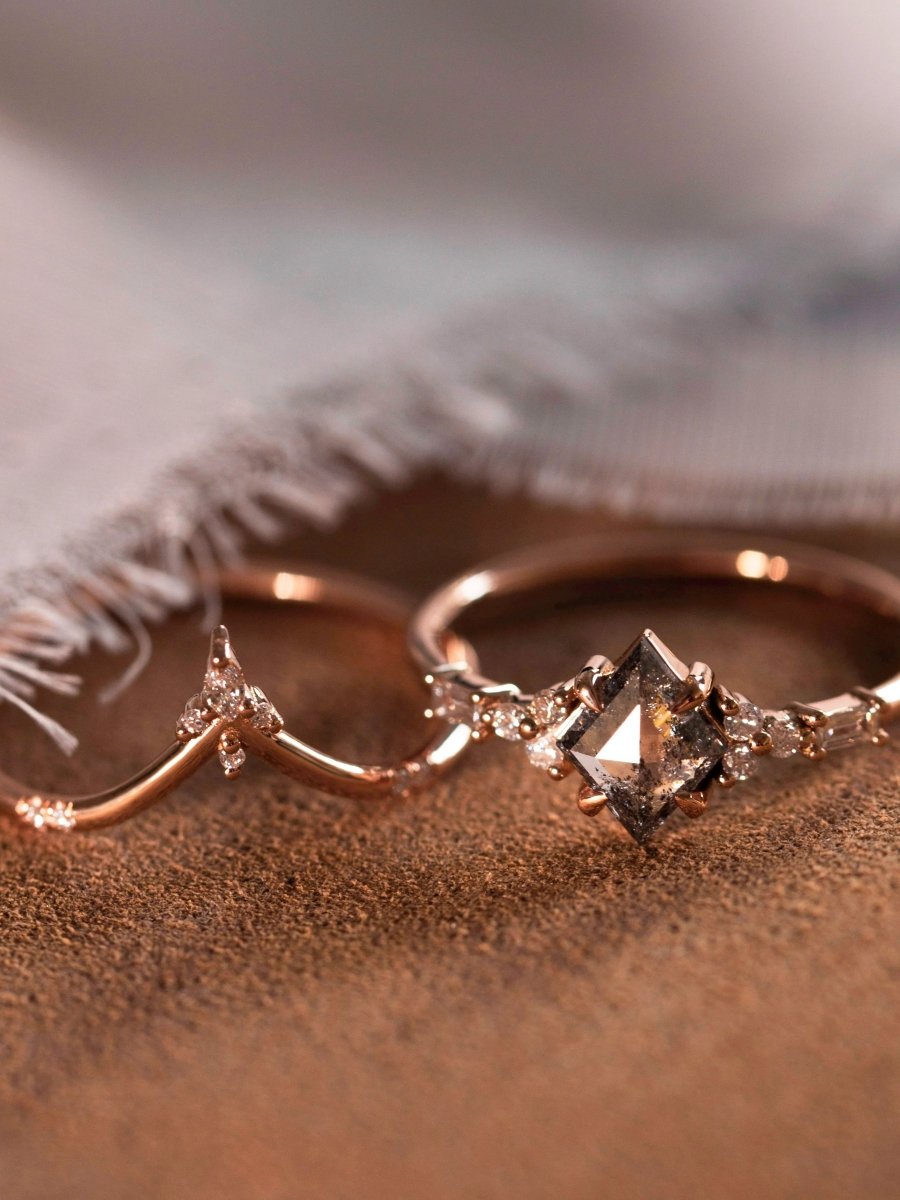 Petite ring with galaxy kite salt and pepper diamond and trefoil melee accents beside chevron band, displayed on brown fabric.