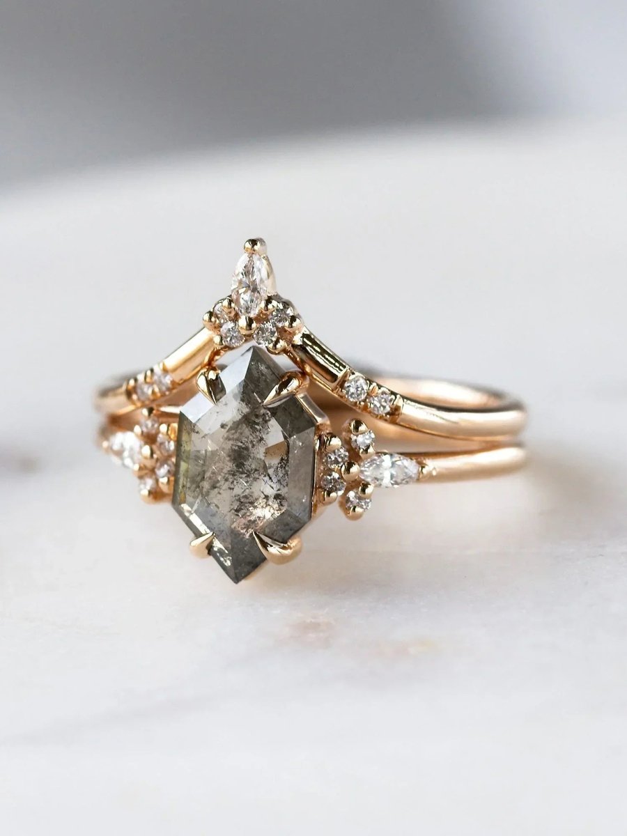 Rose gold ring with a large diamond and smaller diamonds on a marble surface