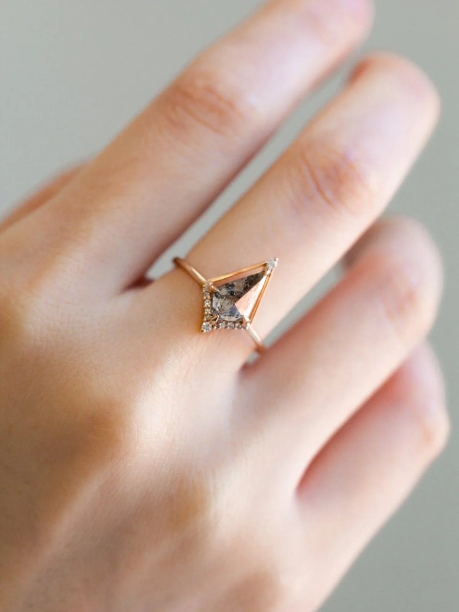 Kite shape salt and pepper diamond engagement ring with smaller round diamonds in 14k gold inspired by the art deco style and minimalism on model’s hand.