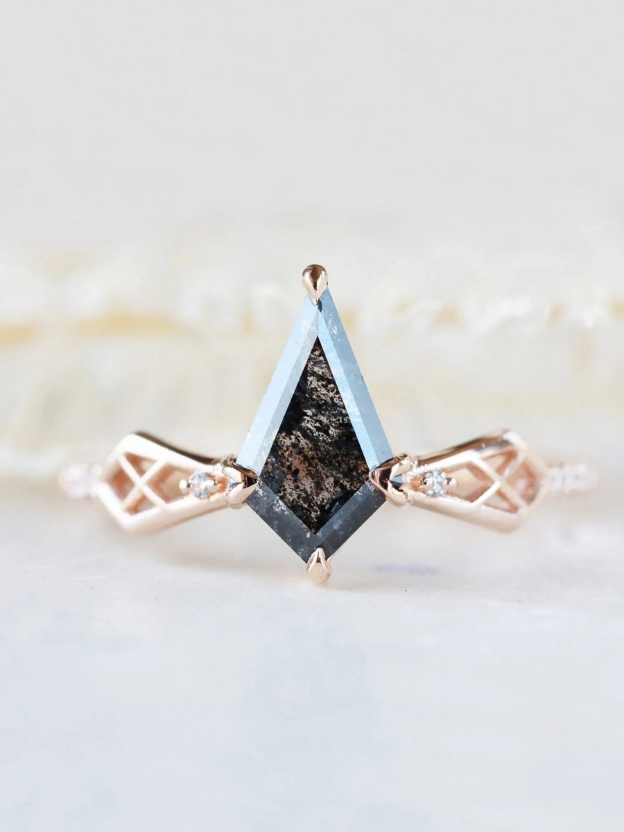 Close-up of salt and pepper kite center stone on modern Art Deco kite engagement ring with geometric latticed shoulders and round melee diamonds out of focus