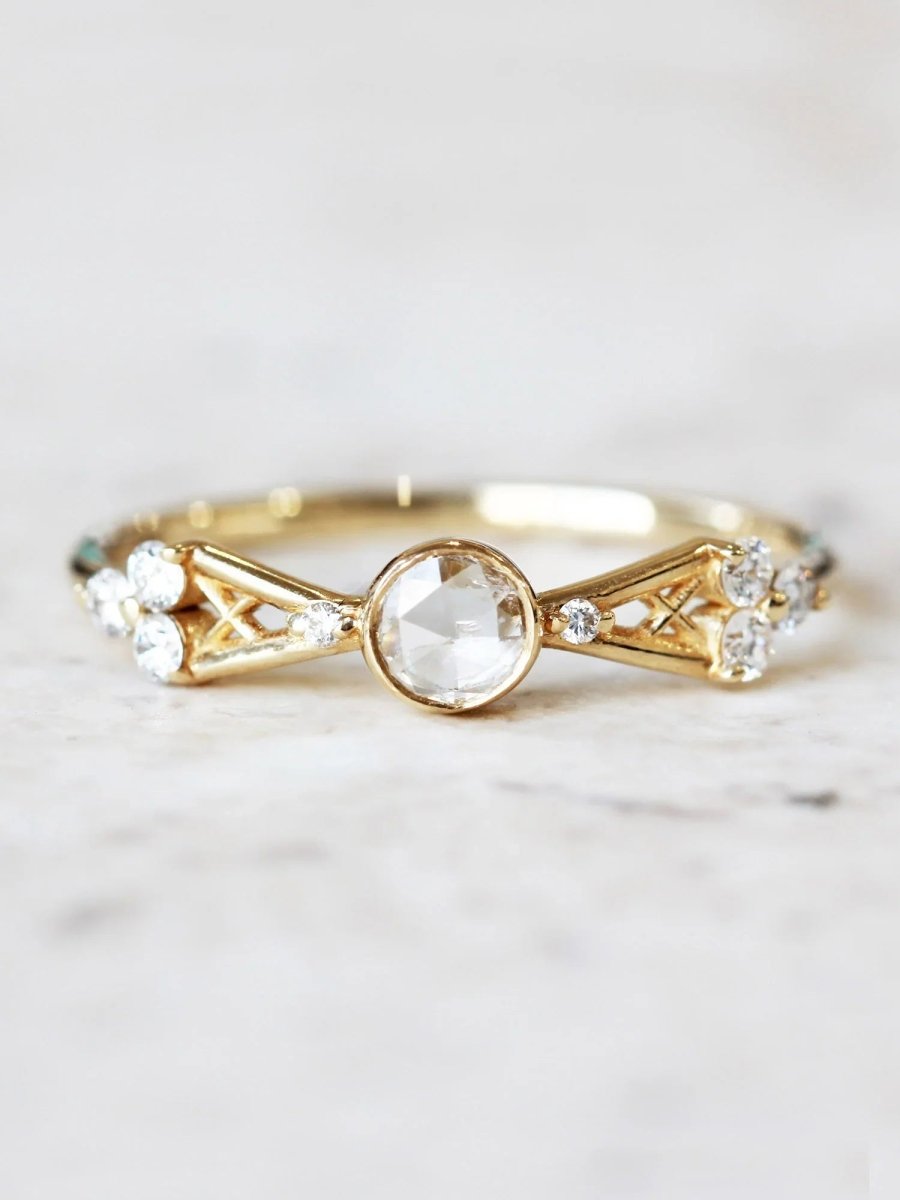 Petite Art Deco yellow gold ring on white marble, showcasing natural light to highlight sparkle and clarity of round center stone