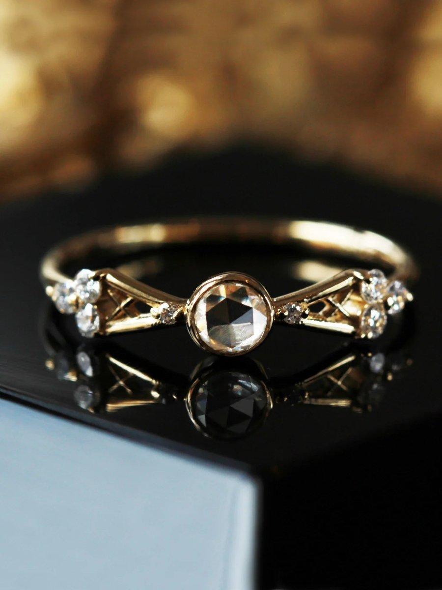 Close-up of petite Art Deco yellow gold ring on black book with gold background, highlighting open-back setting of round center stone